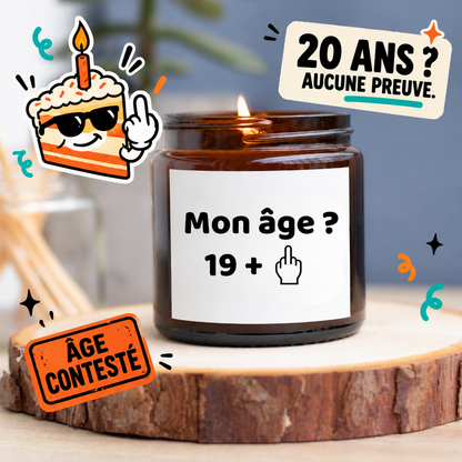 Bougie allumée en pot ambré avec le message Mon âge ? 19 + et un doigt d’honneur, entourée de décorations humoristiques pour un anniversaire de 20 ans.