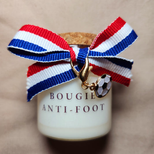 Bougie parfumée humoristique avec l'inscription "Bougie anti foot", allumée dans un salon calme loin des écrans.