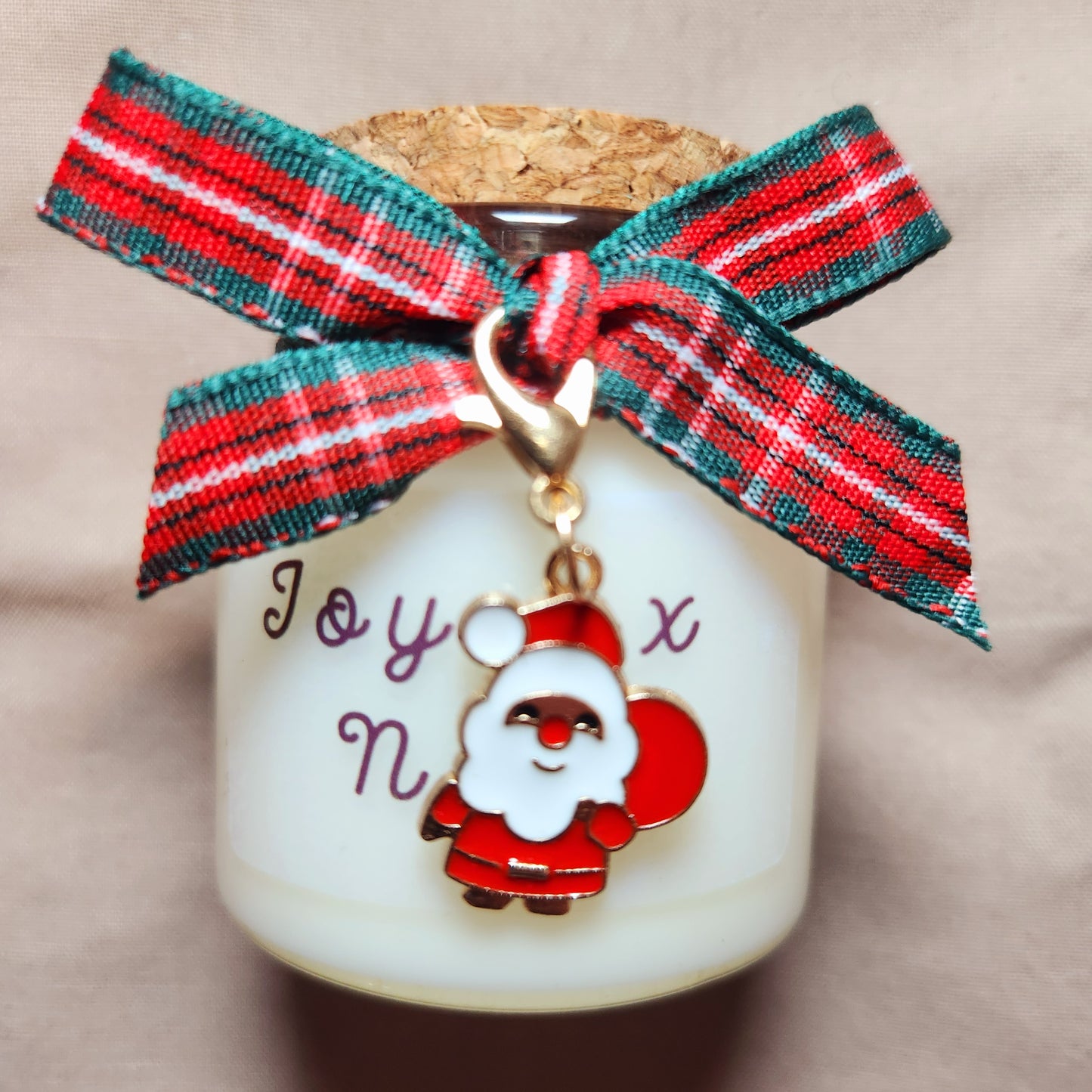 Bougie cadeau Joyeux Noël posée près d'un sapin illuminé dans un salon chaleureux