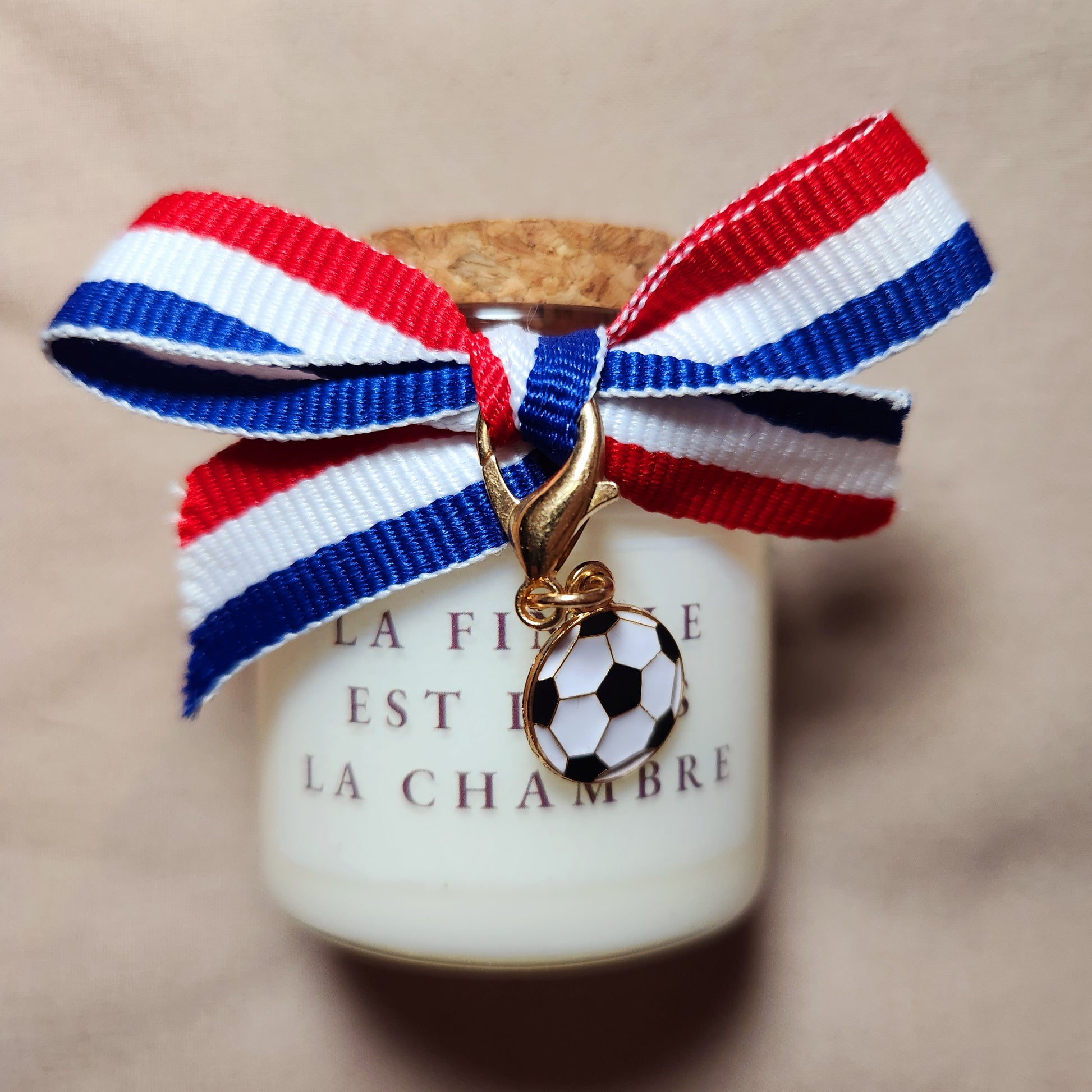 Bougie parfumée en verre avec l'inscription humoristique et coquine "La finale est dans la chambre", style supporter de football, allumée dans un décor chaleureux.