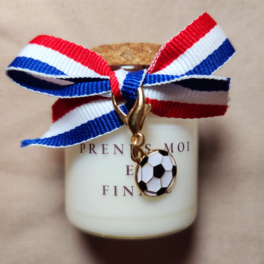Bougie parfumée en verre avec l'inscription osée "Prends-moi en finale", style supporter de football, allumée dans une ambiance tamisée et romantique.