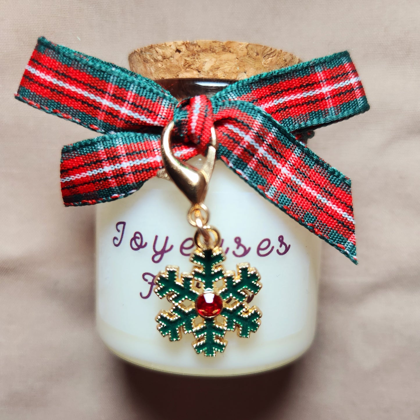 Bougie avec étiquette Joyeuses Fêtes disposée au centre d'une décoration de table de réveillon chaleureuse.