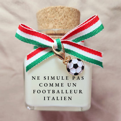Bougie parfumée humoristique avec l'inscription Ne simule pas comme un footballeur italien, décorée d'un élégant ruban en tissu aux couleurs du drapeau de l'Italie.
