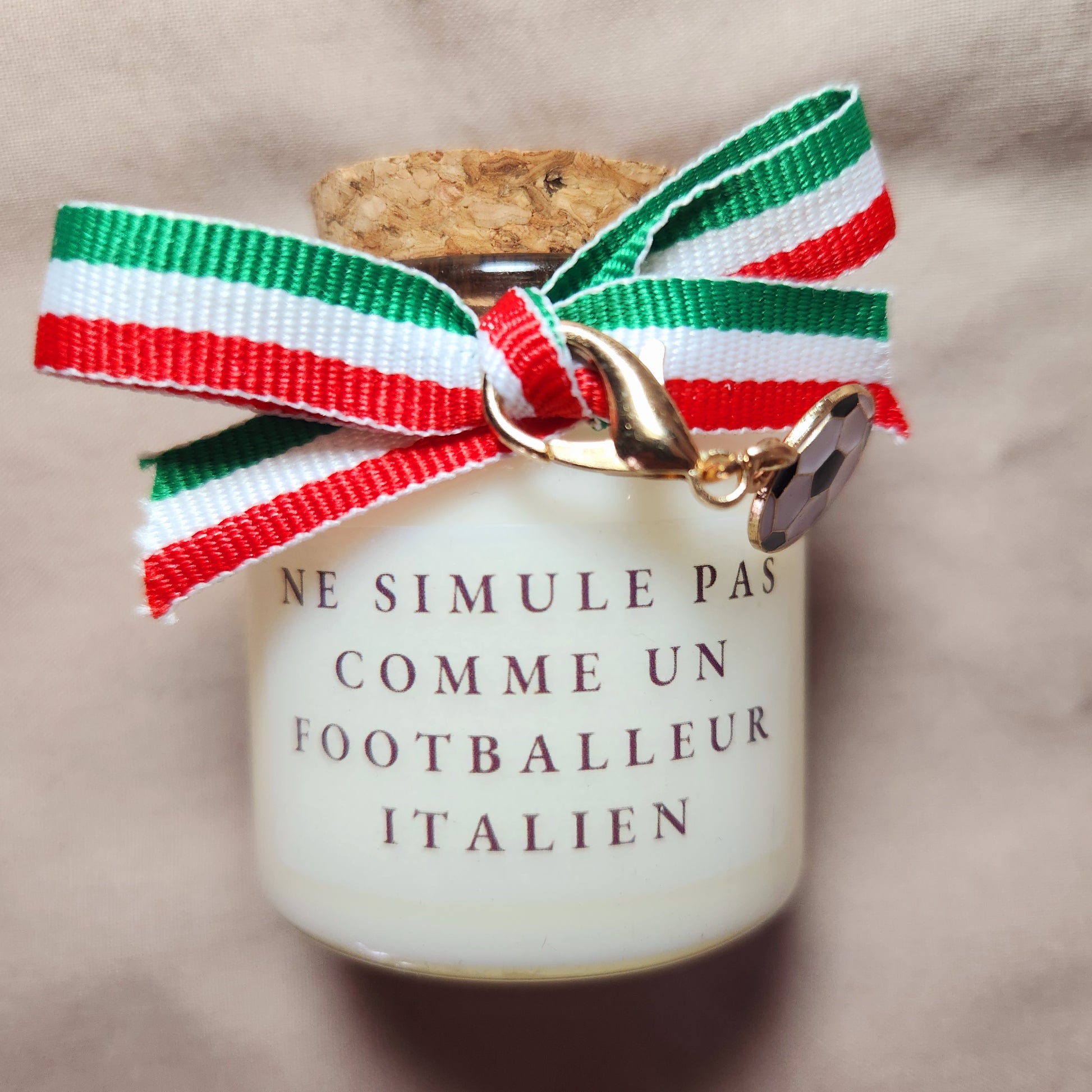 Bougie parfumée humoristique avec l'inscription "Ne simule pas comme un joueur italien", décorée d'un ruban en tissu aux couleurs du drapeau italien (vert, blanc, rouge).