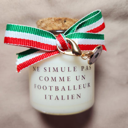 Bougie parfumée humoristique avec l'inscription "Ne simule pas comme un joueur italien", décorée d'un ruban en tissu aux couleurs du drapeau italien (vert, blanc, rouge).