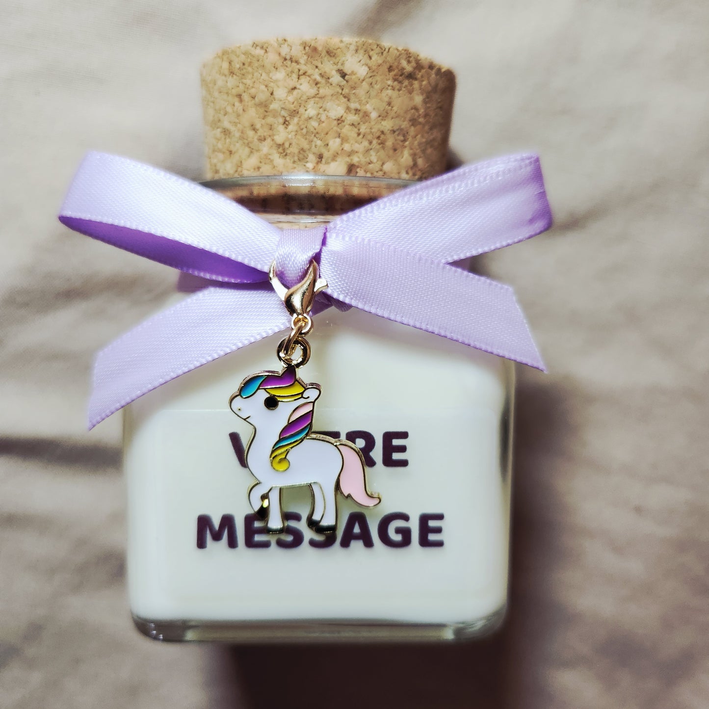 Bougie parfumée licorne grand format posée à côté d'une décoration d'anniversaire pastel