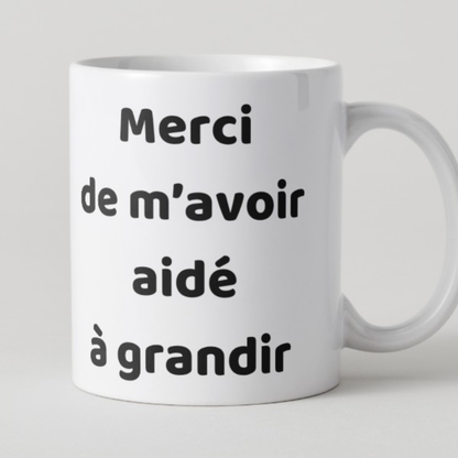 Mug en céramique blanc avec l'inscription colorée Merci de m'avoir aidé à grandir, posé sur un bureau d'école.