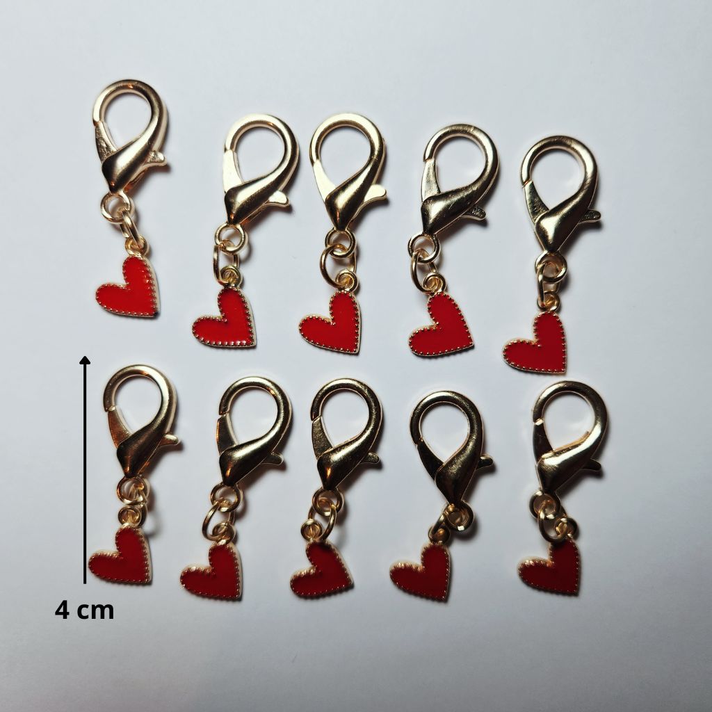 Pendentif en forme de larme dorée abritant un magnifique cœur rouge vif suspendu à un mousqueton.