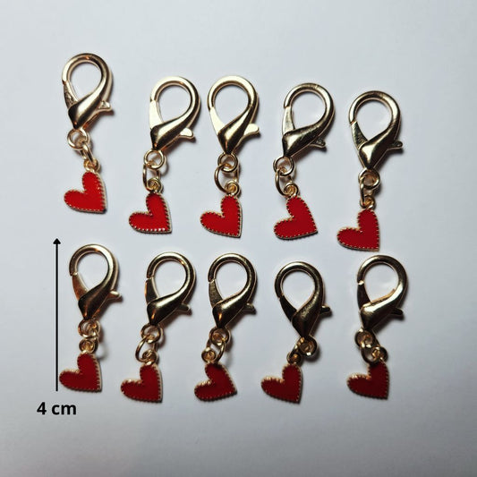 Pendentif en forme de larme dorée abritant un magnifique cœur rouge vif suspendu à un mousqueton.
