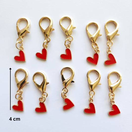 Pendentif en forme de larme dorée abritant un magnifique cœur rouge vif suspendu à un mousqueton.