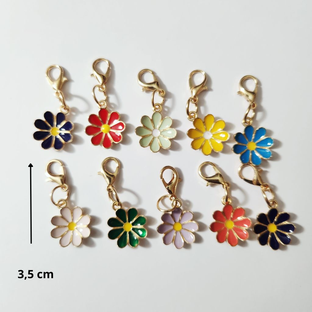 Assortiment de pendentifs en forme de fleurs de marguerites colorées en émail avec contours dorés et fermoirs mousquetons, d'après le fichier fleurs