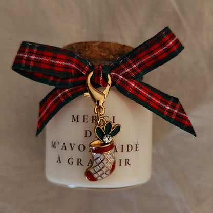 Bougie avec message touchant prête à offrir, posée au pied du sapin de Noël