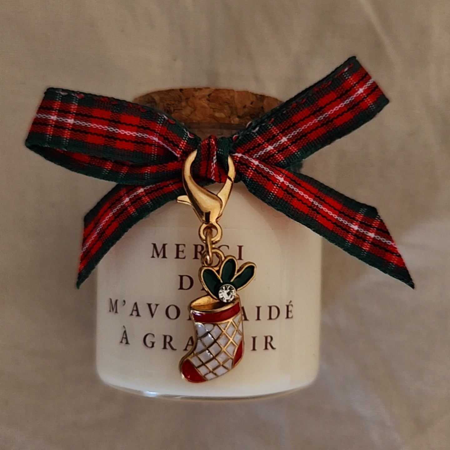 Bougie avec message touchant prête à offrir, posée au pied du sapin de Noël