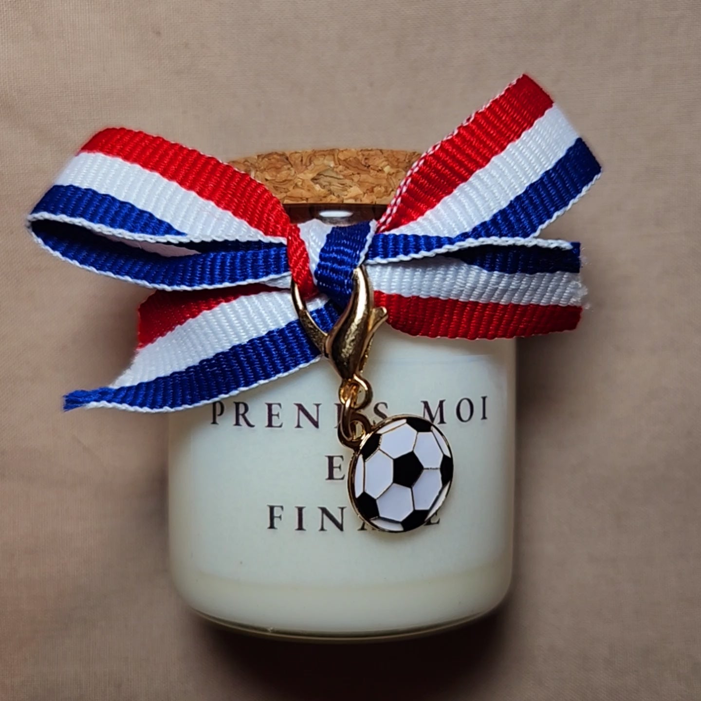 Bougie parfumée en verre avec l'inscription osée "Prends-moi en finale", style supporter de football, allumée dans une ambiance tamisée et romantique. mamiecandle