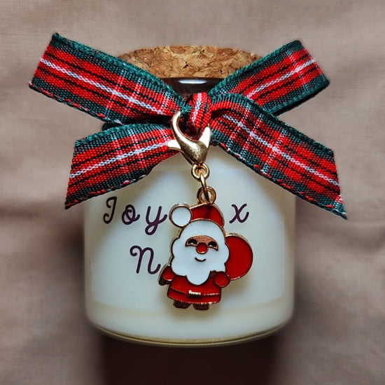 Courte vidéo de la bougie Joyeux Noël allumée, scintillant doucement à côté de paquets cadeaux de fin d'année.