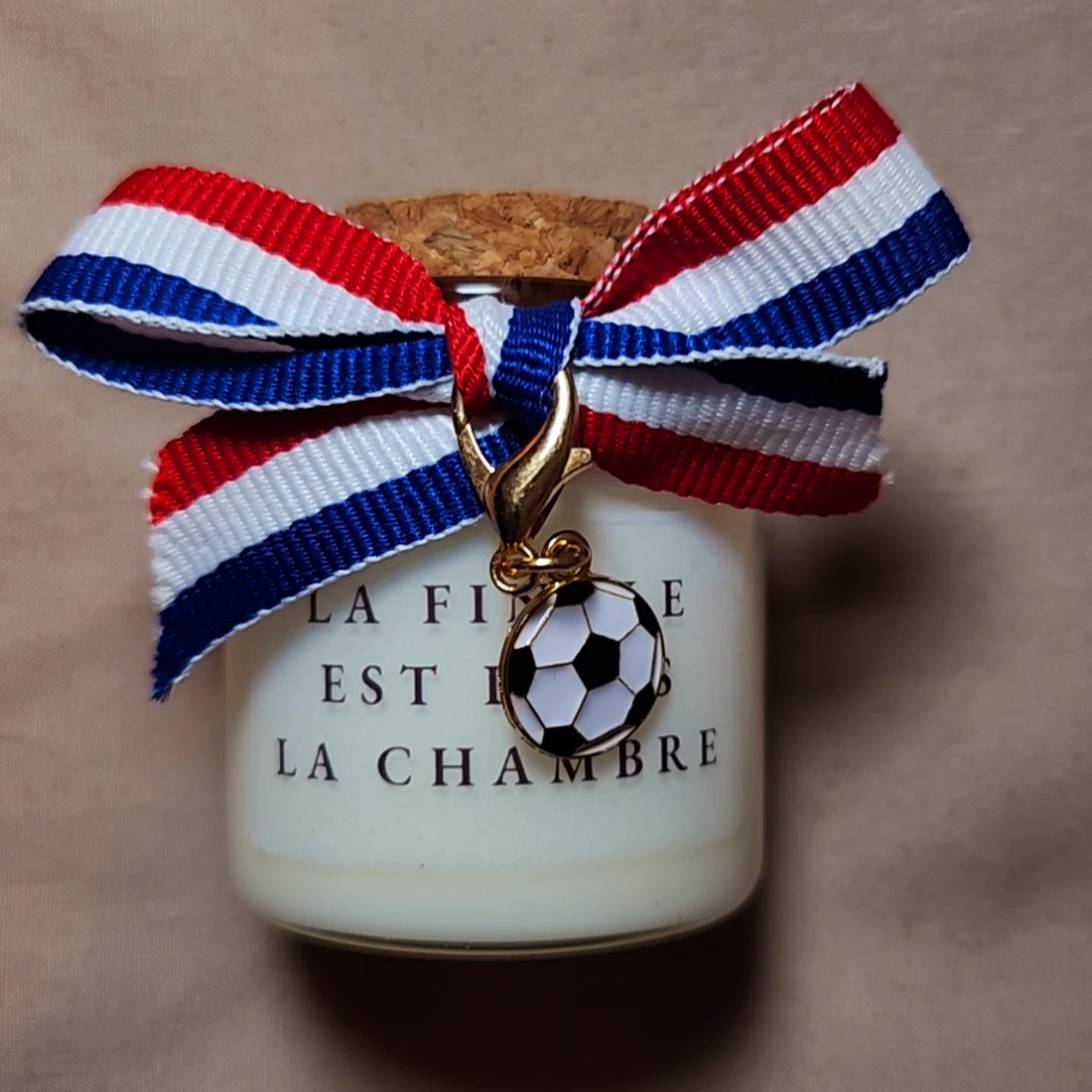Bougie parfumée en verre avec l'inscription humoristique et coquine "La finale est dans la chambre", style supporter de football, allumée dans un décor chaleureux mamiecandle